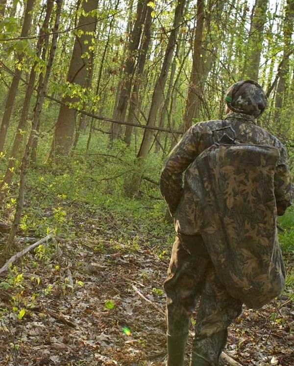Photo of hunter in camo surrounded by forest
