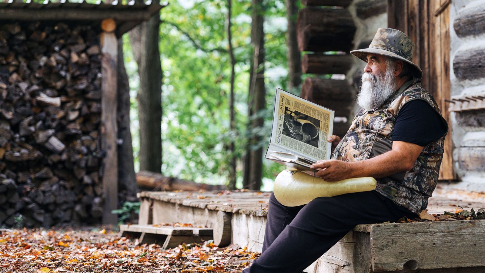 Ken Capling sitting on front porch of cabin with his newspaper article on becoming world champion